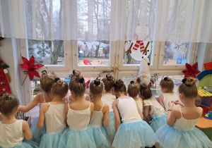 Dziewczynki przebrane za laleczki wyglądające przez okno z bliska