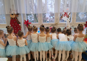 Dziewczynki przebrane za laleczki wyglądające przez okno