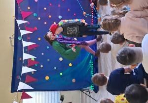 Chłopiec w kapeluszu ogląda się za siebie i śmieje się, bo za nim skrada się aktorka