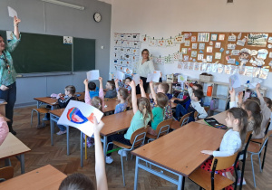 Dzieci podnoszą w górę kartki z pokolorowanymi ptaszkami