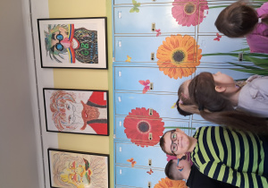 Dzieci idąc przez korytarz mjiają szafki pomalowane w kwiaty i wesołe portrety Pana Kleksa