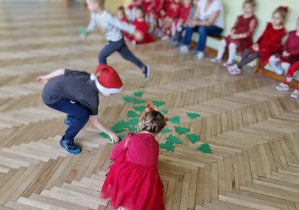 Chłopczyk i dziewczynka zbierają papierowe choinki z podłogi