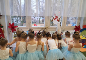 Dzieci przebrane za laleczki wyglądające przez okno z bliska